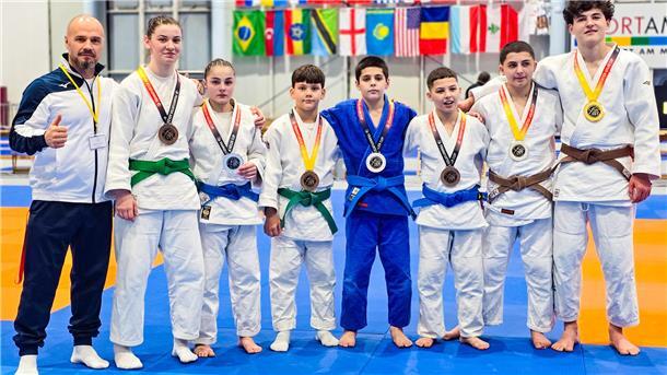 Judoka stehen aufgereiht auf der Matte und haben Medaillen um den Hals. 