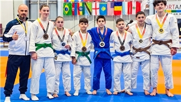 Judoka stehen aufgereiht auf der Matte und haben Medaillen um den Hals. 