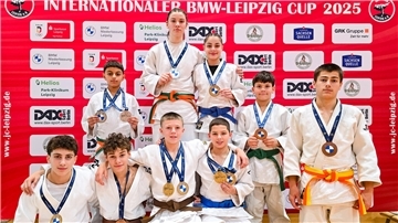 Judoka posieren mit ihren Medaillen für die Kamera.