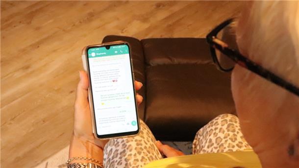 Eine Frau schaut auf ihr Handy und liest eine Nachricht.
