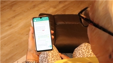 Eine Frau schaut auf ihr Handy und liest eine Nachricht.