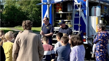 Ein Mann erklärt Kindern und Erwachsenen, was das THW macht.