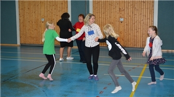 Kinder tanzen in einer Turnhalle.