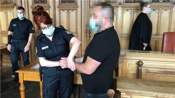 Polizistin legt einem verdächtigen Mann Handschellen an.