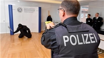 Polizist schießt mit einem Taser. 