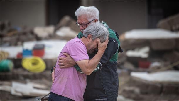 Weinend liegen sich die Brüder Bernd (l) und Gerd Gasper vor ihrem von der Flut zerstörten Elternhaus in den Armen.