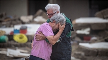 Weinend liegen sich die Brüder Bernd (l) und Gerd Gasper vor ihrem von der Flut zerstörten Elternhaus in den Armen.