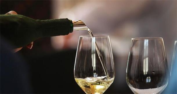  Ein Glas wird mit Weißwein gefüllt. 