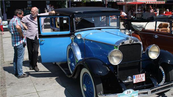 Zwei Männer stehen neben einem Oldtimer.