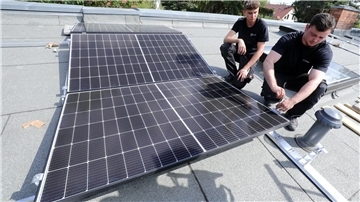Arbeiter installieren Solarpaneele auf einem Dach.
