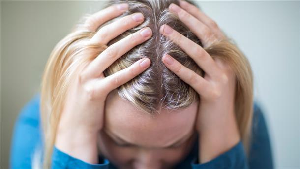 Eine Frau hat den Kopf in die Hände gestützt, Depression.