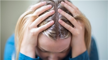 Eine Frau hat den Kopf in die Hände gestützt, Depression.