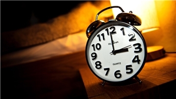  Eine Uhr steht neben einem Bett. 
