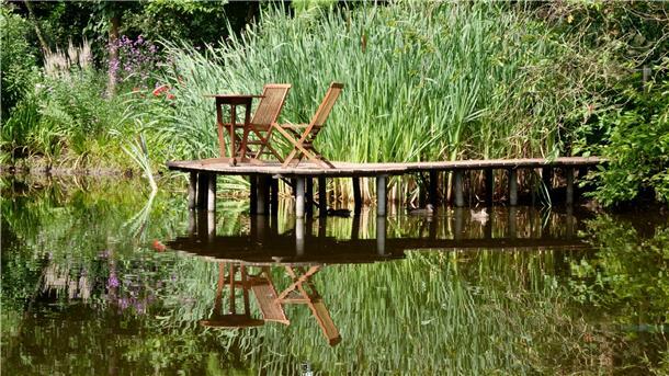 Wer eine Pause machen möchte, findet zahlreiche Sitzgelegenheiten, so wie hier auf einem Steg im Teich.