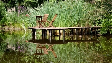 Wer eine Pause machen möchte, findet zahlreiche Sitzgelegenheiten, so wie hier auf einem Steg im Teich.