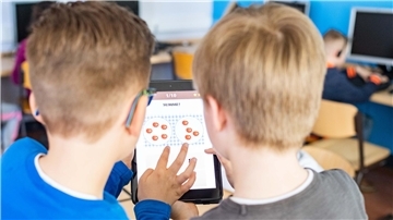 Zwei Schüler arbeiten mit dem Tablet im Unterricht. 