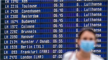 Eine Frau steht vor einer Anzeigetafel im Flughafen. 