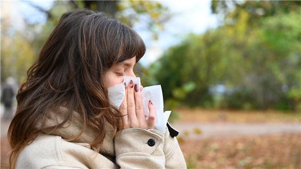 Wer niesen muss, sollte sich von anderen Personen abwenden und ein Taschentuch oder die Armbeuge vor Mund und Nase halten (Symbolbild).