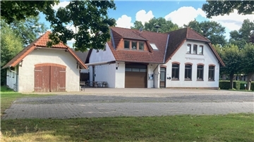 Das aktuelle Feuerwehr- und Dorfgemeinschaftshaus in Kassebruch: Ein weißes Gebäude mit rotem Ziegeldach, daneben ein kleineres Nebengebäude mit Holztoren. Vor dem Haus liegt ein gepflasterter Platz, im Vordergrund eine Rasenfläche.