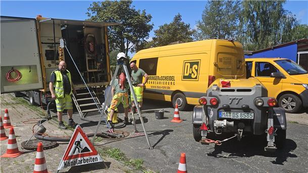Kanalarbeiten in einer Straße mit Fahrzeugen, Maschinen und Arbeitern.
