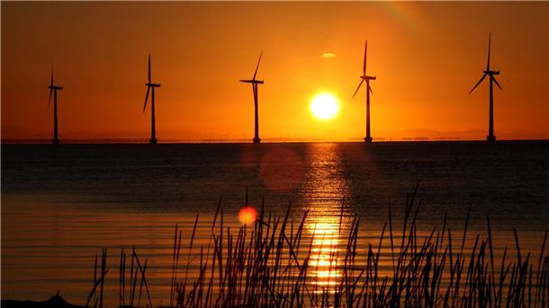 Die Sonne geht hinter Windrädern in Kopenhagen auf.