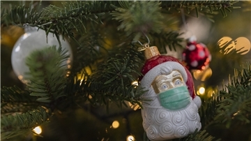 Ein Weihnachtsbaum mit der Christbaumkugel eines Weihnachtsmanns mit OP-Maske.
