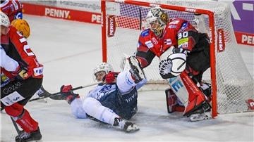 Ein Eishockeytorwart steht im Tor. Davor liegt ein Spieler.