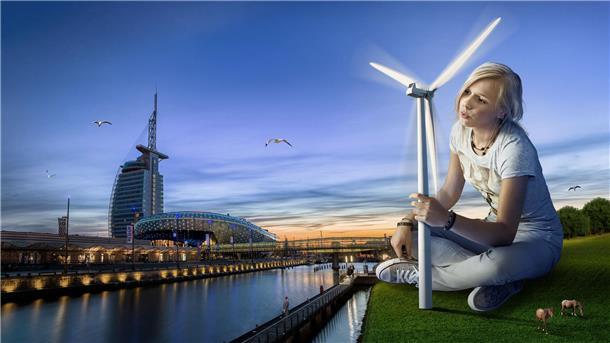 Eine Frau sitzt auf einer grüne Wiese und hält ein Windrad in der Hand. Windenergie als Handlungsoption gegen die Klimakrise - Motiv aus der Werbekampagne, für die das Klimahaus Bremerhaven den German Design Award bekommen hat.