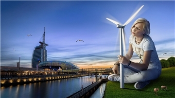 Eine Frau sitzt auf einer grüne Wiese und hält ein Windrad in der Hand. Windenergie als Handlungsoption gegen die Klimakrise - Motiv aus der Werbekampagne, für die das Klimahaus Bremerhaven den German Design Award bekommen hat.