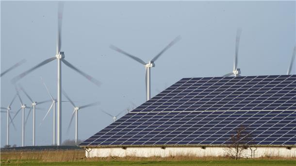 Taskforce legt Vorschläge für schnellere Energiewende vor Windenergieanlagen stehen neben einer Halle mit Photovoltaik-Anlagen.