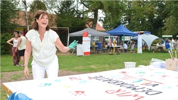 Eine Frau mit Farbe an der Hand steht an einem Plakat