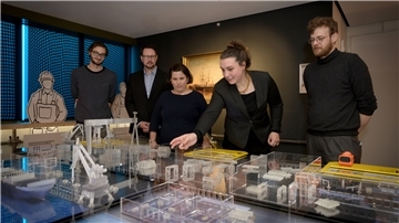 Fünf Menschen stehen vor einem interaktiven Modell einer Werft, ein Ausstellungsstück des Deutschen Schifffahrtsmuseums.