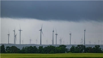  Dunkle Wolken und Regen ziehen über einen Windpark