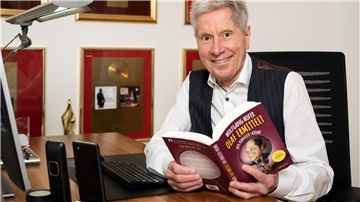 Ein älterer Mann hält ein Buch in der Hand. 