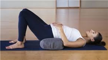 Eine schwangere Frau liegt auf dem Boden und macht Yoga.