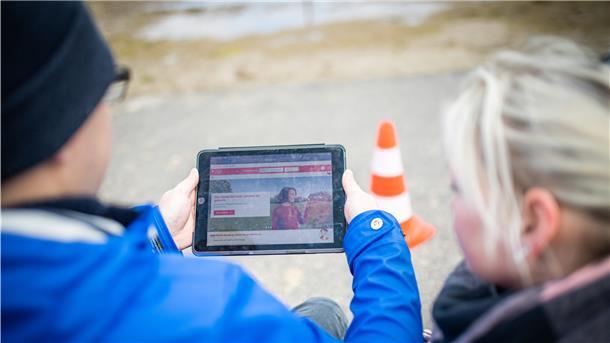 Yvonne und Marvin Holst blicken auf das Tablet mit der Seite der Weser-Elbe Sparkasse.