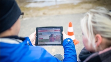 Yvonne und Marvin Holst blicken auf das Tablet mit der Seite der Weser-Elbe Sparkasse.