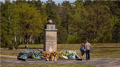 Zahlreiche Blumenkränze liegen um einen Gedenkstein auf dem Gelände der Gedenkstätte Bergen-Belsen.
