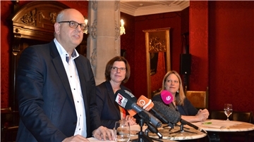 Mann und zwei Frauen am Mikrofon.