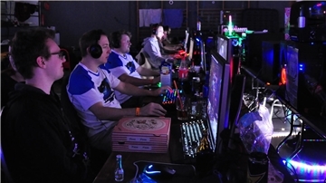Einige junge Computerspielern sitzen nebeneinander vor ihren Bildschirmen und spielen am PC im Netzwerk.