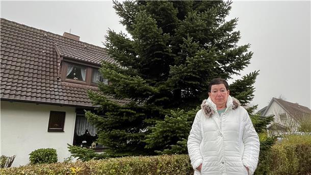 Eine Frau steht vor einer großen Tanne.