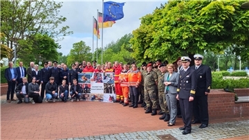 Einsatzkräfte, Politiker, stellen sich zum Gruppenfoto auf.