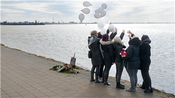 Frauen stehen am Deich und lassen Luftballons aufsteigen. 