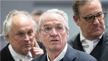 Zum Prozessauftakt gegen die mutmaßliche „Reichsbürger“-Gruppe steht der Hauptangeklagte Heinrich XIII. Prinz Reuß (M) zwischen seinen Verteidigern im Gerichtssaal.