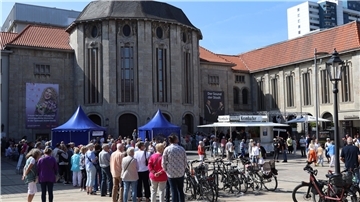 Menschen stehen vor dem Gebäude des Bremerhavener Stadttheaters. 