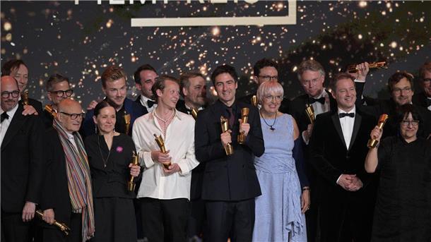 „Das Lehrerzimmer“ gewinnt Deutschen Filmpreis Zusammen mit Kulturstaatsministerin Claudia Roth (im blau-weiß gestreiften Kleid) stehen die Preisträger des Deutschen Filmpreises auf der Bühne.