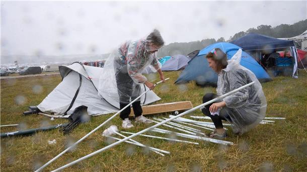 Wetter erschwert Anreise zu Technofestival Nature One Zwei Fans bauen auf dem Campinggelände des Technofestivals „Nature One“ bei strömendem Regen ihr Zelt auf.