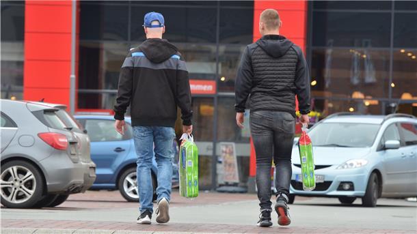 Zwei junge Männer tragen Toilettenpapier über den Parkplatz eines Zevener Supermarktes. In diesen Zeiten kein selbstverständliches Bild.