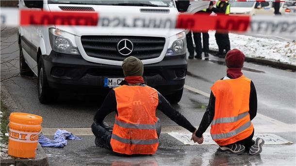 Nach Razzia: „Letzte Generation“ protestiert weiter Zwei Klimaaktivisten der „Letzten Generation“ versuchen, sich auf einer Straße in München trotz Nieselregen und Minusgraden festzukleben.