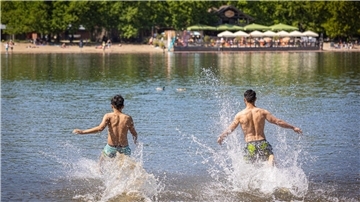 Zwei Männer rennen in einen Badesee. 